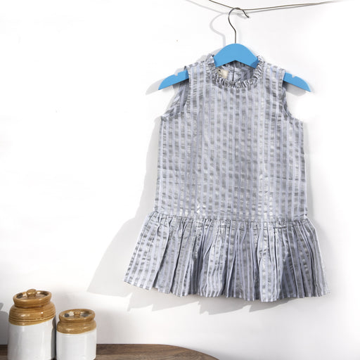 A white cotton mulmul shift dress for kids, hand-block printed with silver stripes..Dress has back button fastenings.
